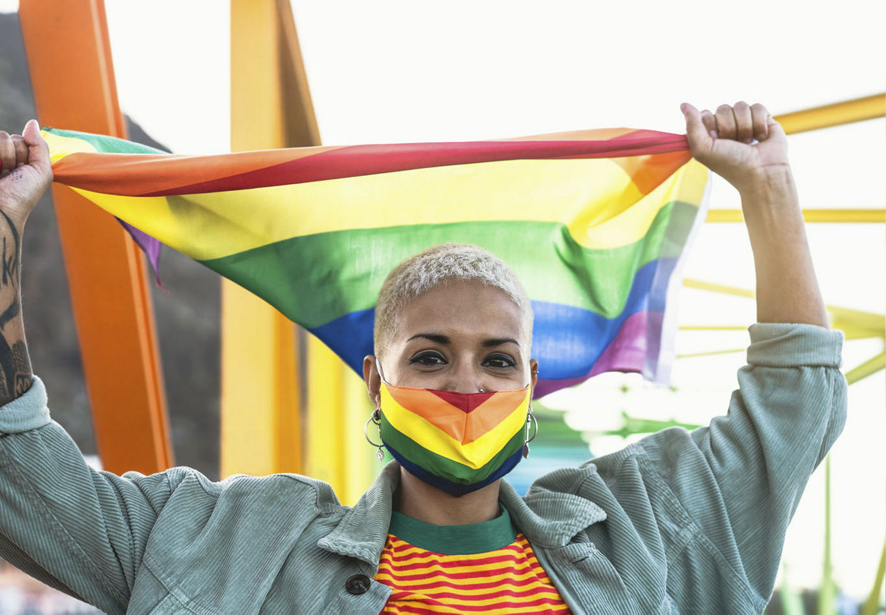 Woman with mask holding rainbow flag  | Blog | Greystar